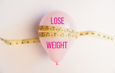 Balloon tied measuring tape on white background. Weight loss, slim body, healthy lifestyle concept....