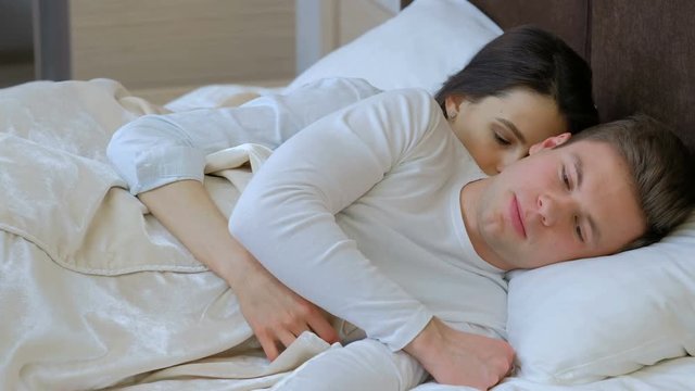 couple intimate problems. young man and woman lie in bed hugging and talking after a quarrel