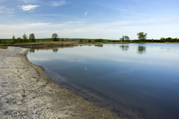 Sand on the shore of the lake, horizon and blue sky