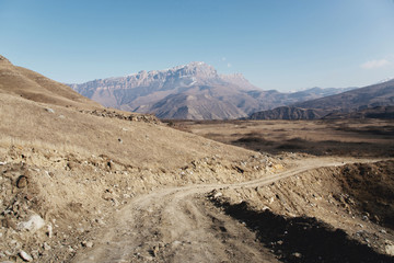 Country road in the mountains against the background of epic rocks