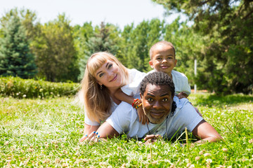 Naklejka na ściany i meble African American happy family: black father, mom and baby boy on nature. Use it for a child, parenting or love concept