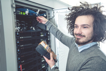 male technician inspecting and working on servers in server room