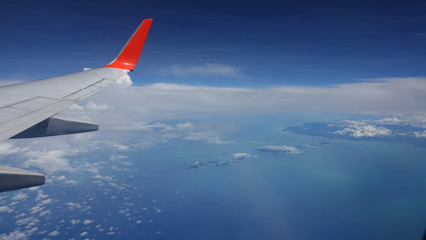POV Looking at a beautiful exotic island and blue sea from a commercial airplane