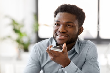 business, communication and technology concept - african american businessman calling or using voice recorder on smartphone at office