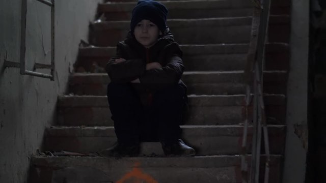 hooligan boy sits alone in an old ramshackle building, demolition house