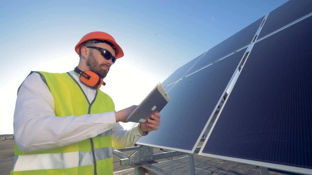 A man on the roof, working, close up. An engineer checks solar panels on the roof.