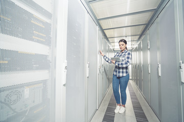 Woman technician working on and inspecting servers in server room