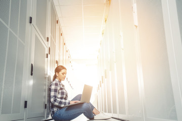 Woman technician working on and inspecting servers in server room