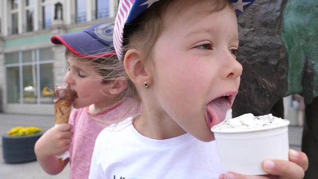 Little boy and girl children funny licking eating ice cream on a street public place