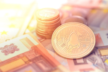 shiny golden ROCKETPOOL cryptocurrency coin on blurry background with euro money