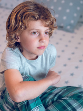 Close up of thoughtful boy sitting on bed