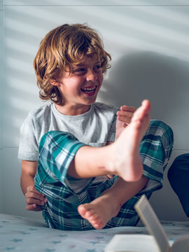 Boy smelling foot on bed