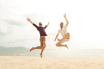 Obraz premium Young energetic happy tourist men jumping at the beach