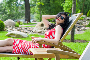50s vintage style woman at yacht club. Pretty pin-up woman with make-up, vintage style in modern life on vacation wear polka dot dress 