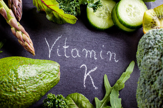 Green vegetables rich in vitamin K on black slate.