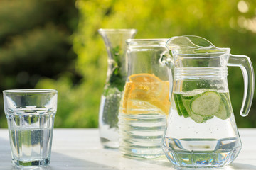 Three variants of fresh homemade lemonade with lemon, cucumber and mint. Lemonade in jugs and...