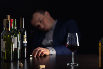 Alcohol abuse by businessman in suit. Silhouette drunk man with glass of wine on first plan.