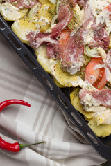 Preparation Potatoes with meat, vegetables and greens with cream sauce on a roasting dish. Flat lay.