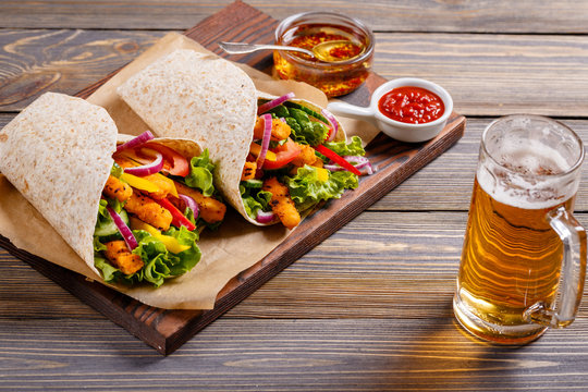 Tortilla with chicken and vegetables and beer to drink.