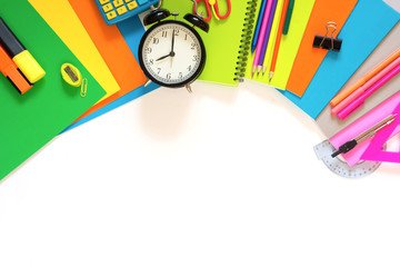 Colorful school supplies, book, and alarm clock on white. Top view, flat lay. Copy space.