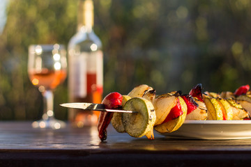 Grilled veggies kebab with zucchini, onions and sweet red peppers cooked outdoors on a wooden table...