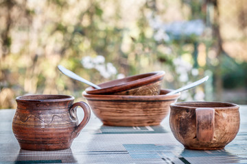 Clay cup, jar and plates with spoons on the table