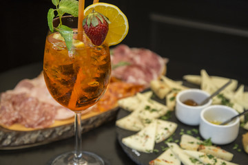 Traditional italian aperitif with proscioutto, mortadella sausage, cheese and aperol spritz drink