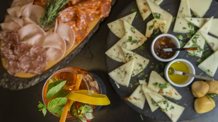 Traditional italian aperitif with proscioutto, mortadella sausage, cheese and aperol spritz drink