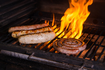 Grilled sausage on the flaming grill. BBQ with fiery background, close up