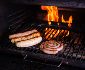 Grilled sausage on the flaming grill. BBQ with fiery background, close up