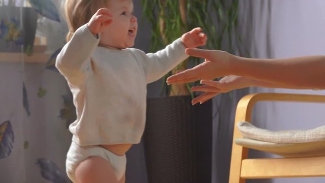 happy cute kid makes his first independent steps to his mother