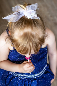 Top view on cutle little blond girl with her lollypop
