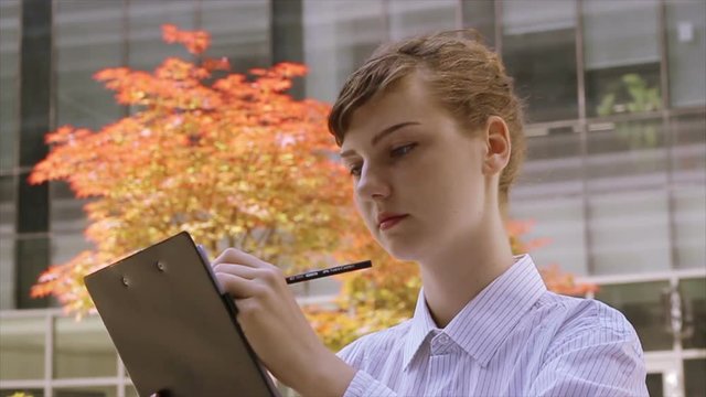 Business woman taking note on Clipboard.
