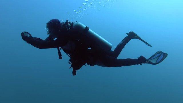 Female scuba diver swims in blue water, Indian Ocean, Maldives
