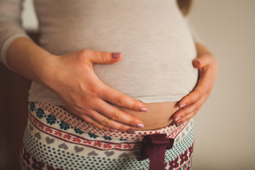 pregnant woman holding hands with her belly