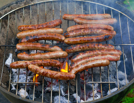 BBQ-Sausages cooking on charcoal barbecue part burned.