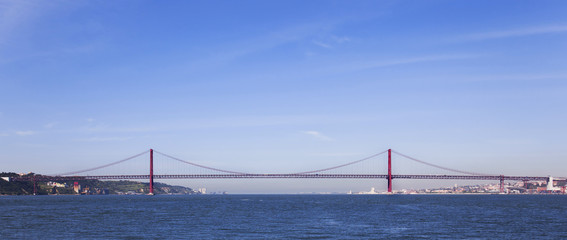 Ponte 25 de Abril Bridge profile in Lisbon, Portugal. Connects the cities of Lisbon and Almada crossing the Tagus River. View from the middle or center of the river.
