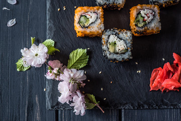sushi and sakura branch on a black wooden background