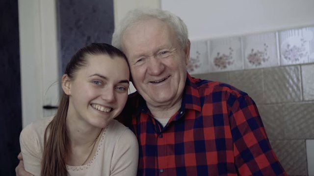 Portrait of old father and young daughter smiling at camera. 4K