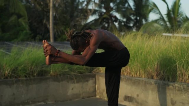 Man do standing head to knee yoga pose roof top solar battery rapid slow motion