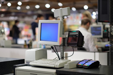 Rows of cash desks with cashiers and customers on blurry background