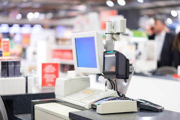Cash desk terminal  with cashiers and customers on blurry background