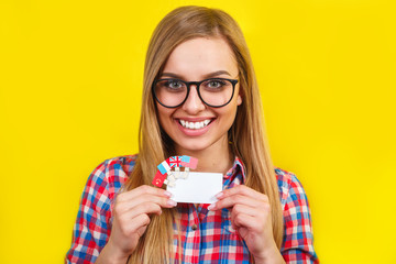 Young woman with card and flags of different speaking countries. Studio portrait of young beautiful female student on yellow background