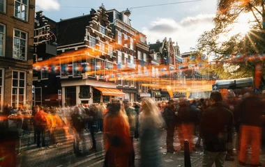 Poster de jardin Amsterdam Rues d& 39 Amsterdam pleines de gens en orange lors de la célébration de la fête des rois. Personnes floues au coucher du soleil avec des décorations de lumière du soleil et orange.