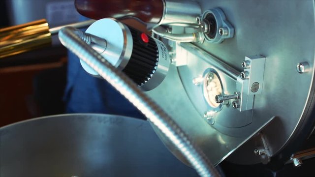 Professional coffeemachine and raw coffee beans. White coffee beans are fried in a professional machine for coffee beans to make real coffee. Slow motion.