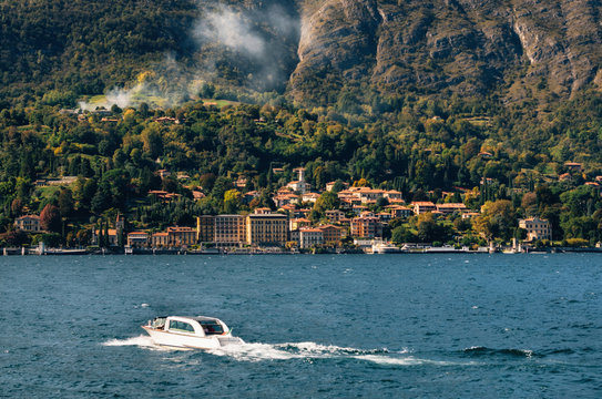 Boat moves against Cadenabbia town with buildings and hotels, coast of beautiful Como lake, Italy.