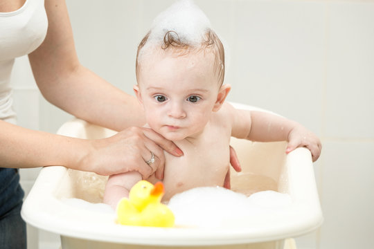 Funny portrait of 10 months old baby boy washing in bathtub