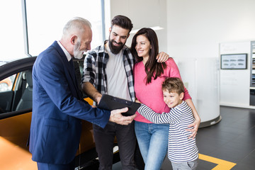 Happy family buying a new car at the car showroom.