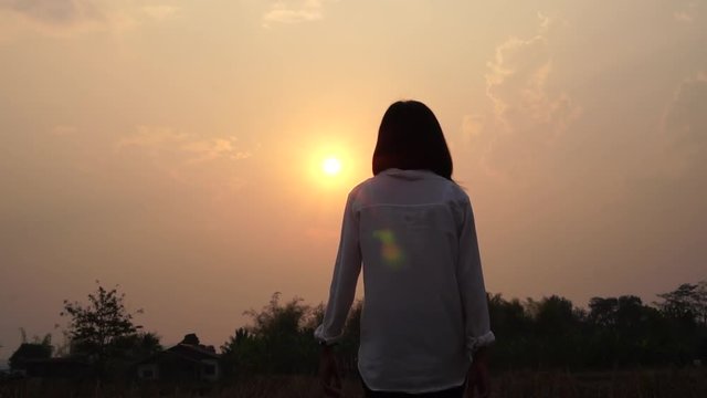 People freedom style Concept : Silhouette of Asian Young woman relaxing, Strong confidence open her arms and watching sunset scene in summer sunset sky outdoor, slow motion shot