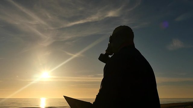 man in gas mask reading book silhouette distancing camera